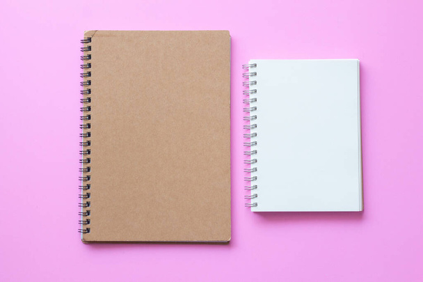 коричневая обложка ноутбука с открытым чистым блокнотом бумаги на розовом фоне. - Фото, изображение