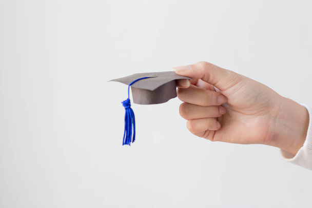 Hand holding graduation hat on white background. - Foto, immagini