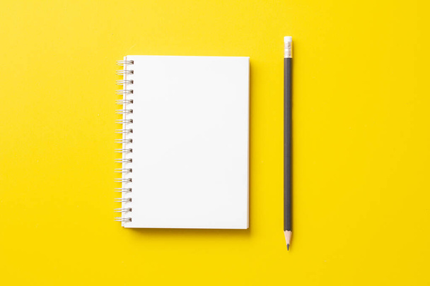 Blanco notitieboekje met potlood op gele achtergrond.Minimale stijl.Bovenaanzicht.  - Foto, afbeelding