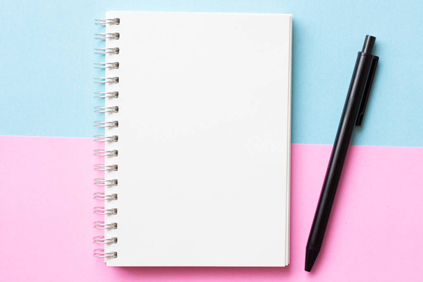 Flat lay of Notebook with pen on pastel blue and pink color background, minimal style. Work space duo tone. - Фото, изображение