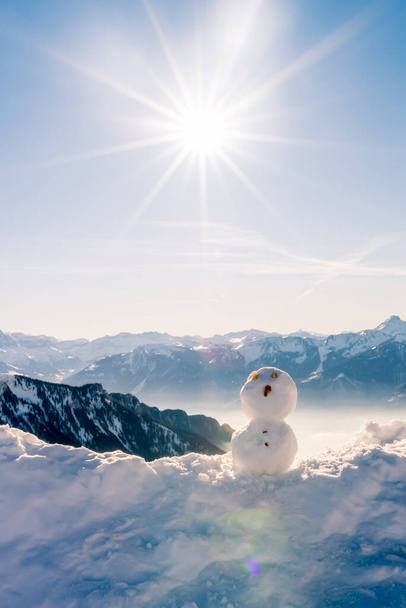 クリスマスの日に雪だるま。山と霧の背景と冬の雪男。楽しさと幸せなコンセプト。スイスのローチャー・ド・ナイ。子供時代と休日のコンセプト. - 写真・画像