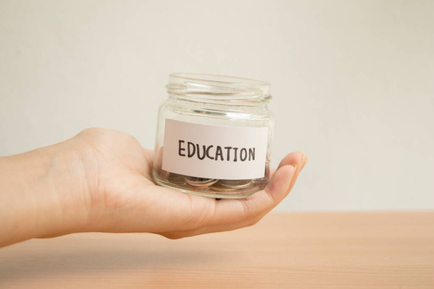female holding saving glass jar scholarship for education in future on wood table,vintage,minimal. - Foto, immagini