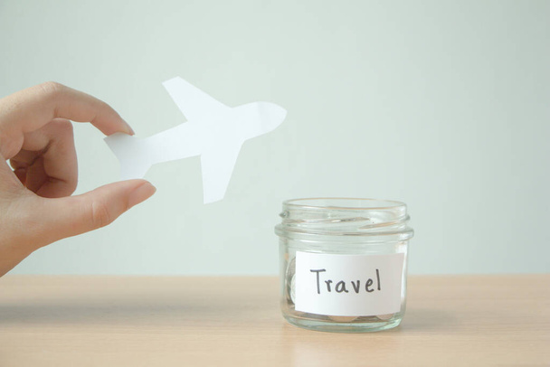 Hand holding paper cut of airplane with saving money for travel.  - Valokuva, kuva