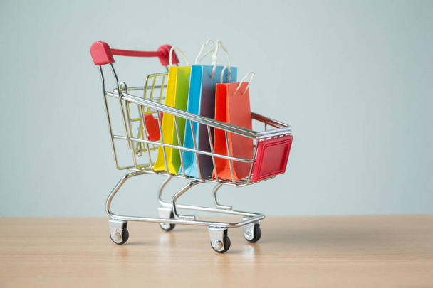 Πολύχρωμες τσάντες ψώνια χαρτί σε ένα τρόλεϊ ή καλάθι αγορών, E-commerce έννοια. - Φωτογραφία, εικόνα