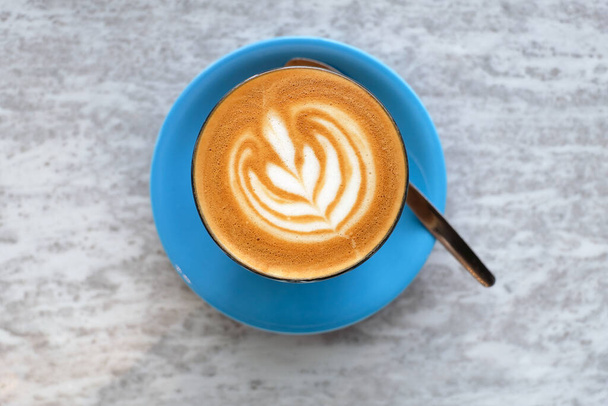 Красивый последний художественный кофе подается в синей чашке - Фото, изображение