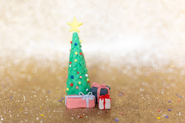 Playful clay christmas concept. Colorful handmade miniature Christmas tree and presents in gold background. - Fotoğraf, Görsel