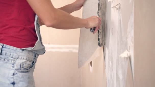 Nainen tekee korjauksia talossa ja repii vanhan tapetin seinästä. - Materiaali, video