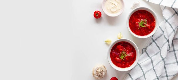 Traditional home Ukrainian beet soup with fresh green dill. Russian borscht in bowl of tomatoes, sour cream, and mushrooms on a white background with copy space. - Fotó, kép