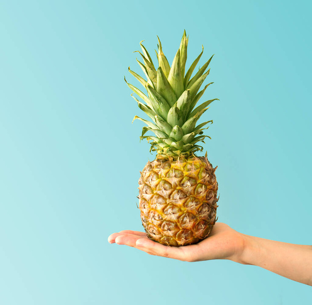 Kézen fogva egy ananászt. A kreatív elrendezés ananászból készült. Lapos fekvés. Élelmiszer-koncepció. - Fotó, kép
