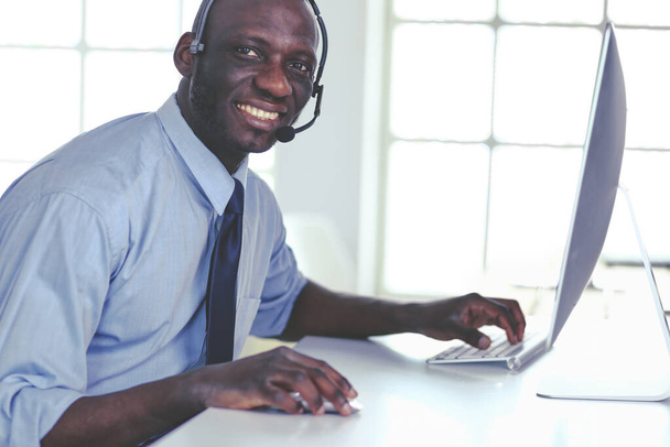 African american businessman on headset working on his laptop - Photo, image