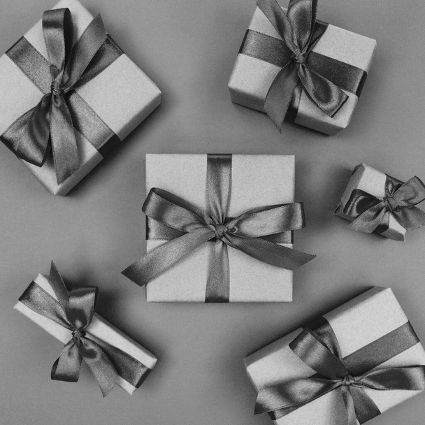 Gift boxes wrapped in craft paper with a black ribbons and bows. Festive monochrome flat lay. - Photo, Image