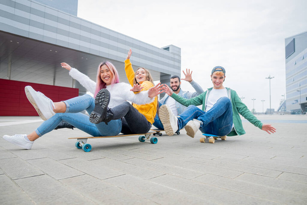 Группа подростков, валяющих дурака в скейт-парке - Счастливые молодые друзья, сидящие на скейтборде - Группа веселых друзей, развлекающихся, концепции о подростке, образе жизни и поколении z - Фото, изображение