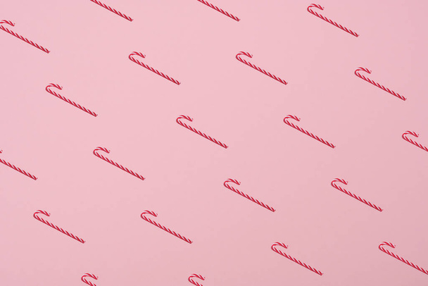 Pattern of Candy canes on pastel pink background. Minimal style. Christmas concept. - Фото, зображення