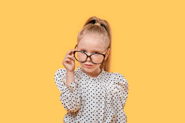 A blonde girl with glasses for vision looks at the camera. Black-rimmed glasses. - Photo, Image