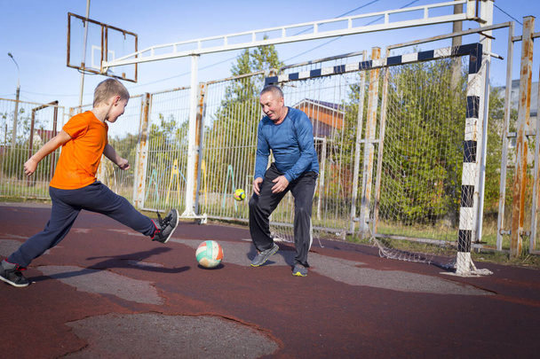 Active senior man playing football with his grandson - Photo, image