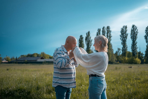senior man holding and kissing woman hand on date in park - Φωτογραφία, εικόνα