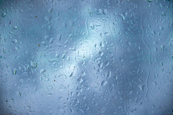 Regendruppels op het glas en water lopen door het glas, de fotografie en de achtergrond. Regen, water, natuur en regenachtig weer, foto 's - Foto, afbeelding