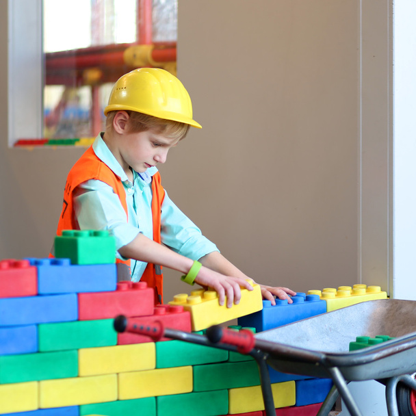 Boy building a house with big plastic construction bricks - Foto, afbeelding