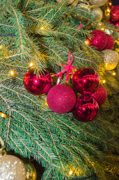Schattige Kerst sprankelende rode en gouden glazen ballen op natuurlijke sparren takken achtergrond, authentieke kerst achtergrond met sparren takken en decoraties, verticale frame. - Foto, afbeelding