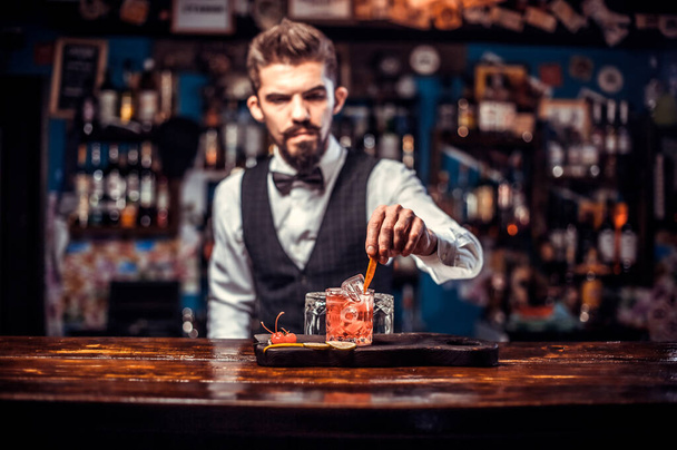 El camarero joven mezcla un cóctel mientras está de pie cerca del mostrador del bar en el bar - Foto, imagen