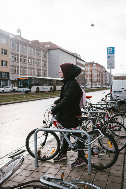Young woman picks up her bike from the parking lot - Zdjęcie, obraz