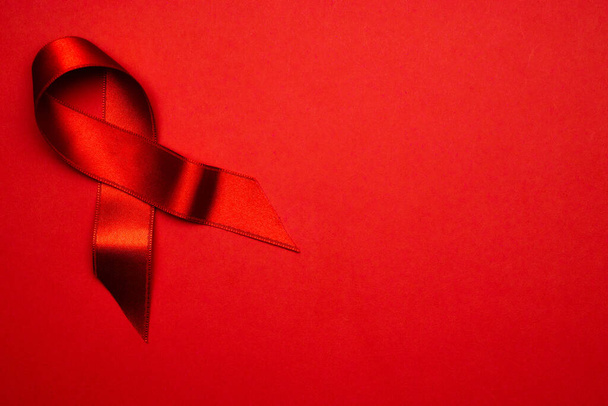 Breast cancer woman. Red ribbon symbol in hiv world day on dark red background. Awareness aids and cancer. Healthcare and medical concept - Photo, Image