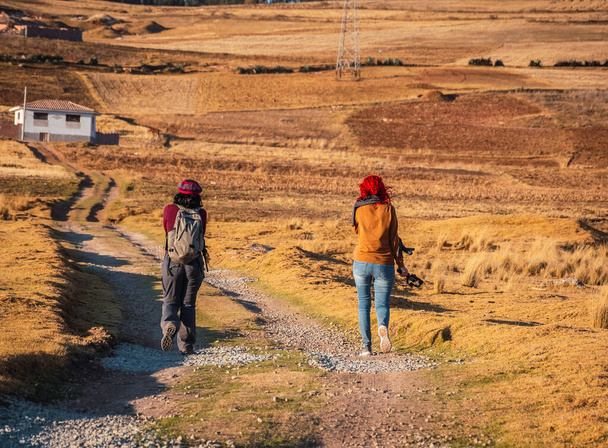 Peru vadilerinde sıcak bir güneş ışığıyla yürüyen iki kadın. - Fotoğraf, Görsel