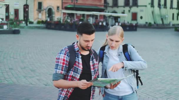 Un paio di turisti in possesso di mappa e alla ricerca di un posto sulla piazza della città - Filmati, video
