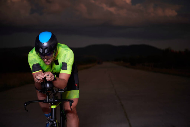 triathlon athlete cycling fast riding professional racing bike at night - Photo, Image
