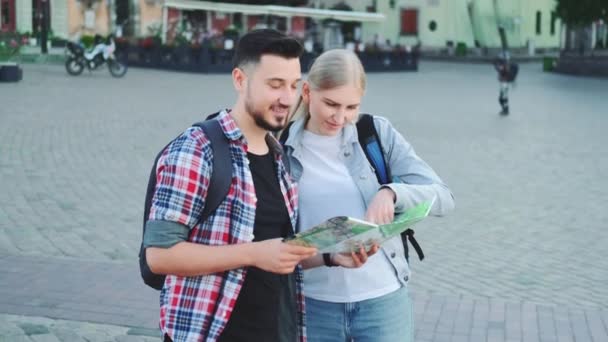 Coppia di turisti in possesso di mappa per trovare un nuovo luogo interessante per visitare la città - Filmati, video