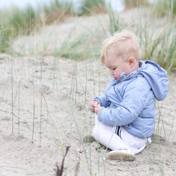 Baby girl plays with sand in the dunes - Photo, image