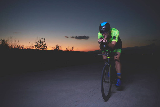 triathlon athlete cycling fast riding professional racing bike at night - Fotoğraf, Görsel