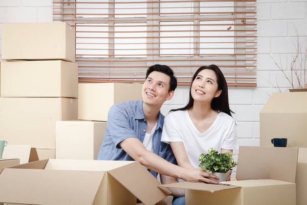 Aasialainen pari siirtymässä uuteen kotiin Apua purkaa ruskea paperi laatikko sisustaa talon. Ajatus uuden elämän aloittamisesta, perheen rakentamisesta. Kopioi tila - Valokuva, kuva