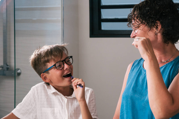 Stock photo of young boy and his mother cleaning their teeth in the bathroom while looking at each other. - Foto, Bild