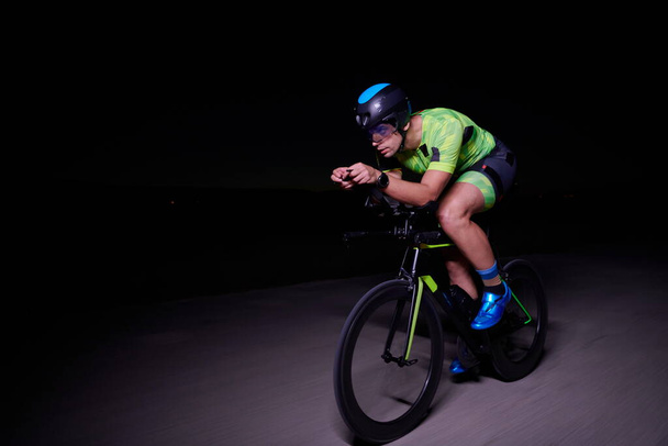 triathlon athlete cycling fast riding professional racing bike at night - Foto, Bild