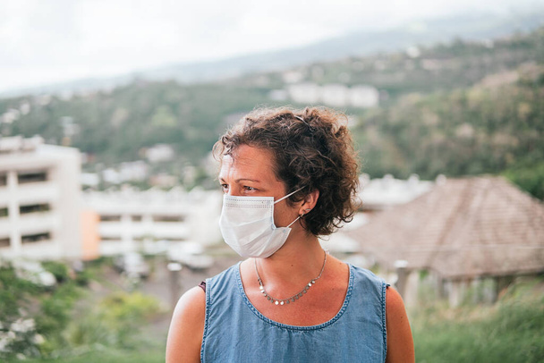 Stock photo of adult woman wearing disposable face mask due to covid19 looking to the side. - Photo, Image