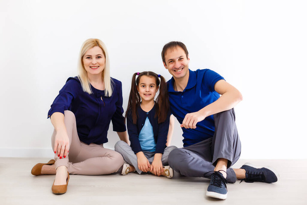 Üç kişilik mutlu bir ailenin portresi gülümseyerek kameraya bakıyor. - Fotoğraf, Görsel