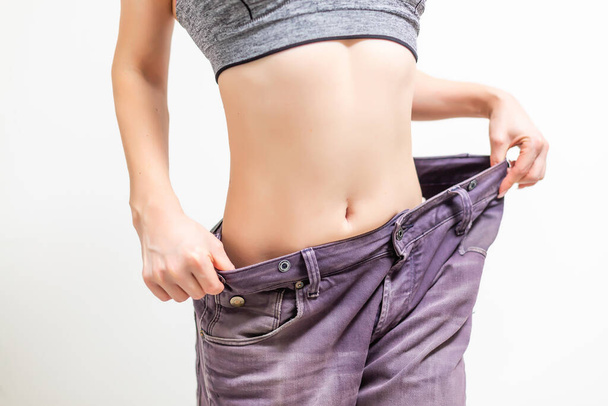 fitness, dieta, perda de peso e conceito de pessoas - jovem mulher esportiva magro em calças de tamanho grande - Foto, Imagem