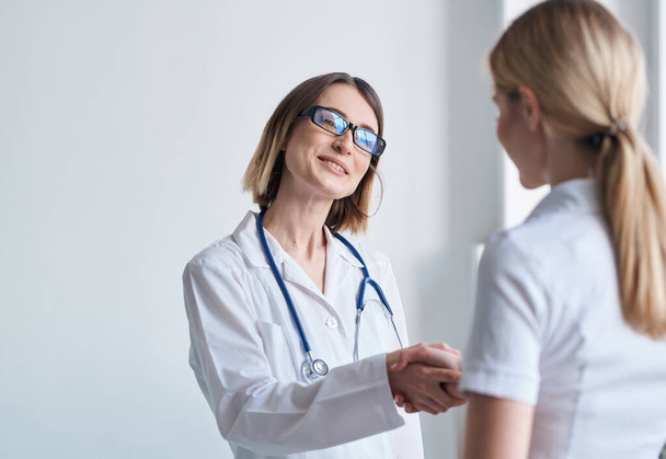 vrouw arts schudt handen met patiënt in wit t-shirt - Foto, afbeelding