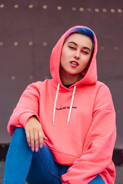 Young girl with short colorful hair and nose piercing dressed in pink hoodie - Фото, изображение