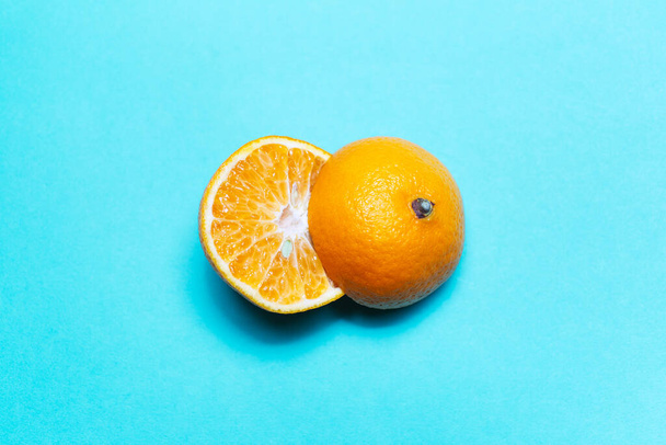 Close-up of two halves of orange fruit on background of cyan color. - Foto, afbeelding