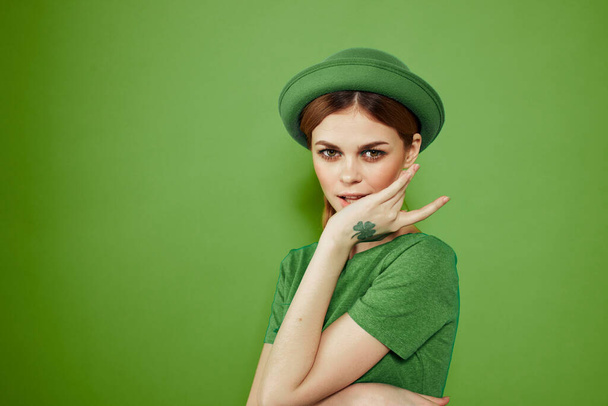 Buena chica con un trébol en la mano en un fondo verde vacaciones St. Patricks día divertido sombrero en su cabeza  - Foto, imagen