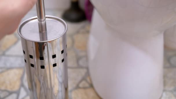 Weibliche Hand nimmt weiße Toilettenbürste aus Chromkolben. Nahaufnahme - Filmmaterial, Video