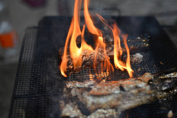 Der gebackene Fisch wird auf einem Drahtgestell über offenem Feuer gebraten - Foto, Bild
