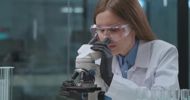 virologista feminina está explorando vírus de covid-19 em laboratório médico, visualizando-o em microscópio, pesquisa de coronavírus - Filmagem, Vídeo