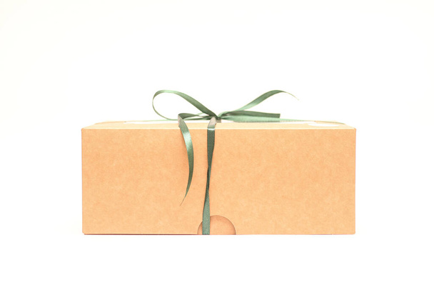 Craft-Geschenkbox mit einem grünen Band auf weißem Hintergrund gebunden. Studiofoto einer Geschenk-Seitenansicht - Foto, Bild