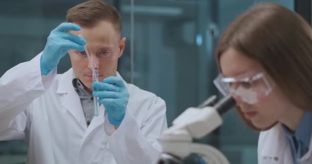 man and woman scientists are working in chemical laboratory, researching and experimenting with reagents - Footage, Video