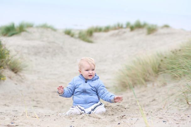 Baby girl plays with sand in the dunes - Photo, image