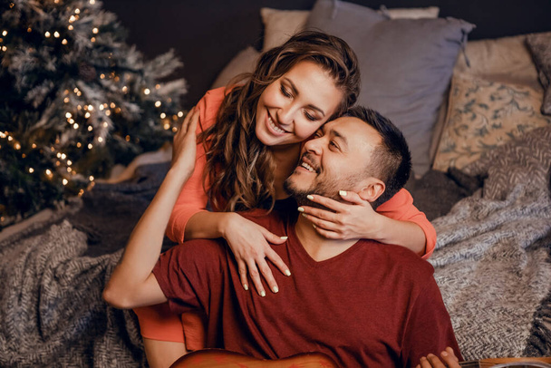 Una joven pareja celebra la Navidad en una acogedora casa de campo concepto de vacaciones de invierno y vacaciones familiares. Ambiente festivo. - Foto, imagen