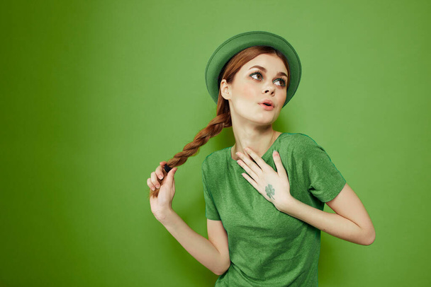 Kedves lány egy lóhere a kezét egy zöld háttér ünnepek St. Patricks Day szórakoztató kalap a fején  - Fotó, kép